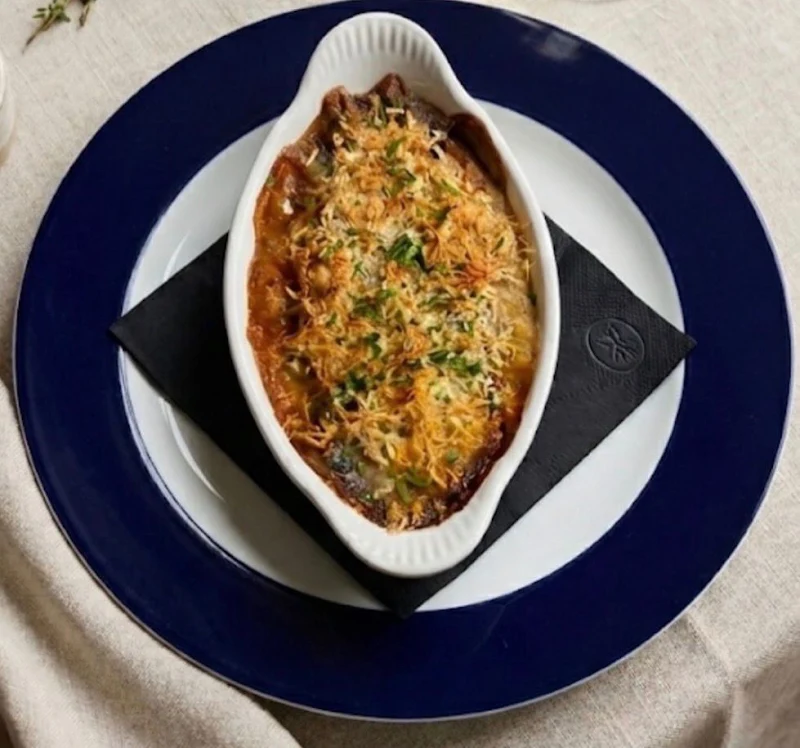 Un gratinado en cazuela blanca, sobre plato azul